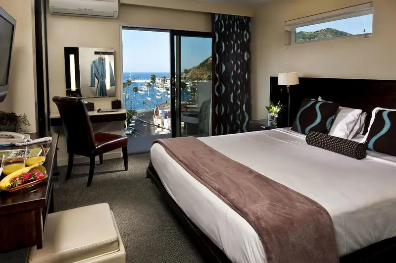 Une chambre avec un grand lit face à une baie vitrée donnant sur la mer.