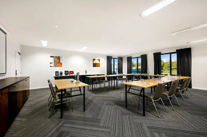 Une salle de réunion lumineuse avec des tables et des chaises alignées.