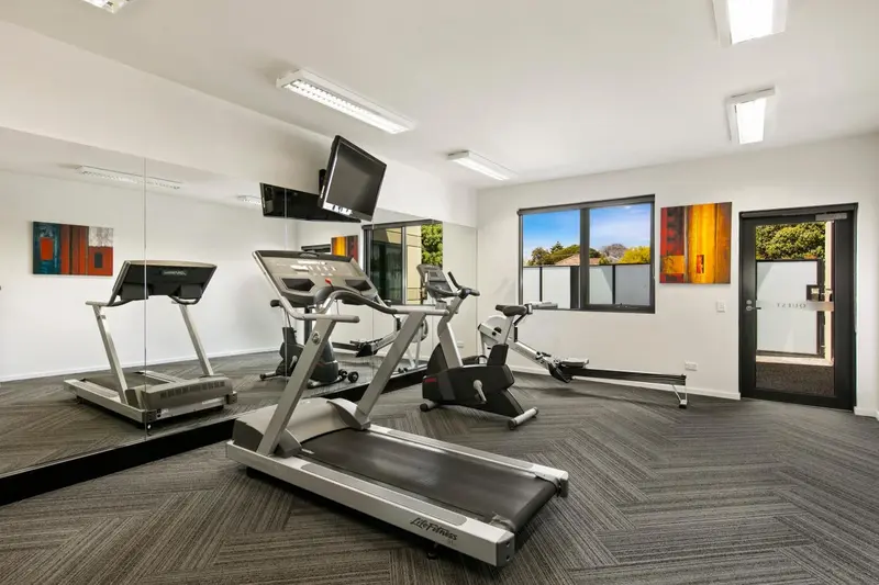 Une salle de sport lumineuse avec des équipements de fitness et des œuvres d'art murales.