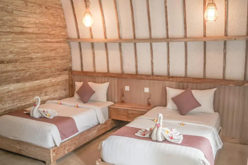 Deux lits simples décorés de serviettes en forme de cygnes dans une chambre.