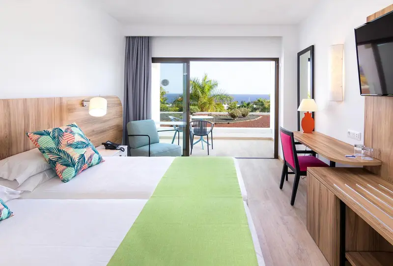 Une chambre lumineuse avec un lit et un accès à une terrasse.