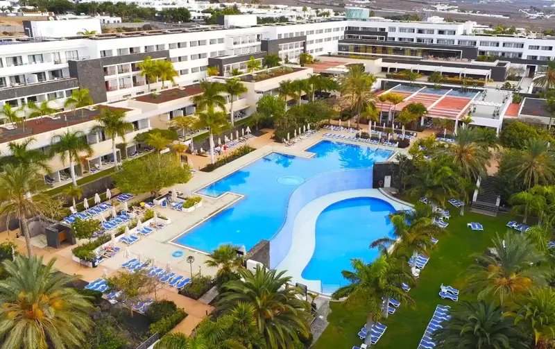 Vue aérienne d'un complexe hôtelier avec piscine et végétation luxuriante.