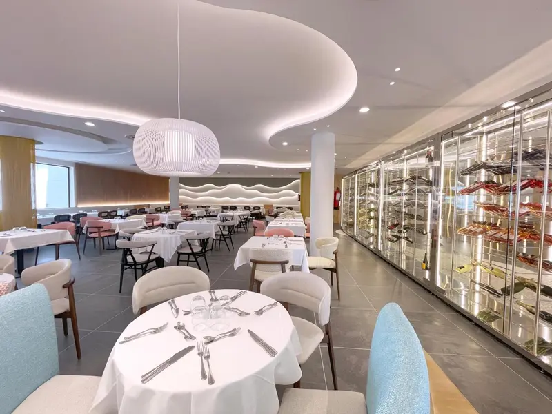 Une salle lumineuse avec des tables dressées pour un repas.