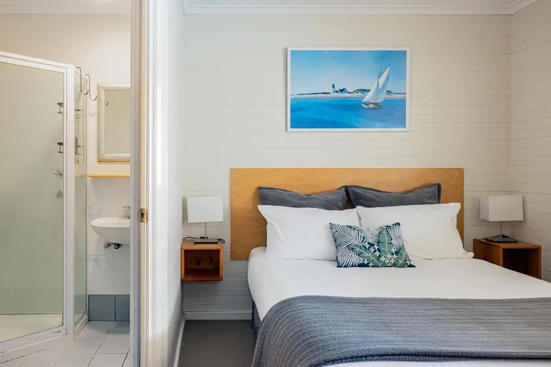 Une chambre lumineuse avec un lit double et une salle de bain attenante.