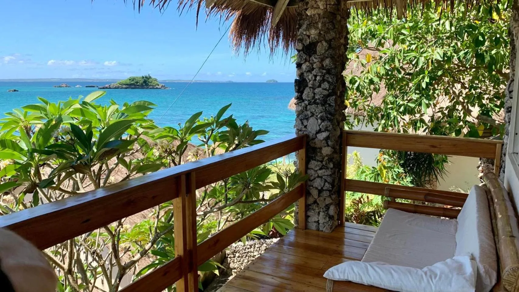 Terrasse en bois avec banc et vue sur la mer et les îles.
