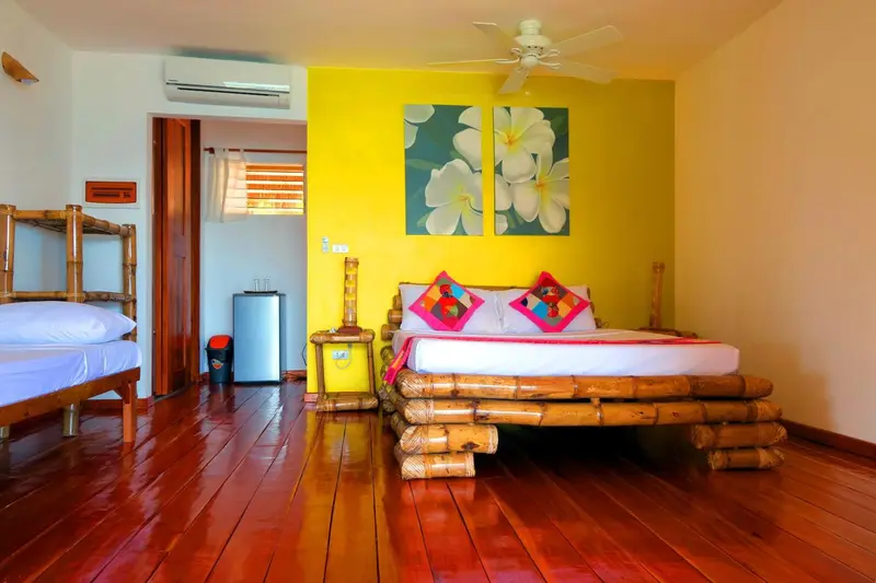 Une chambre lumineuse avec un lit en bambou et des coussins colorés.