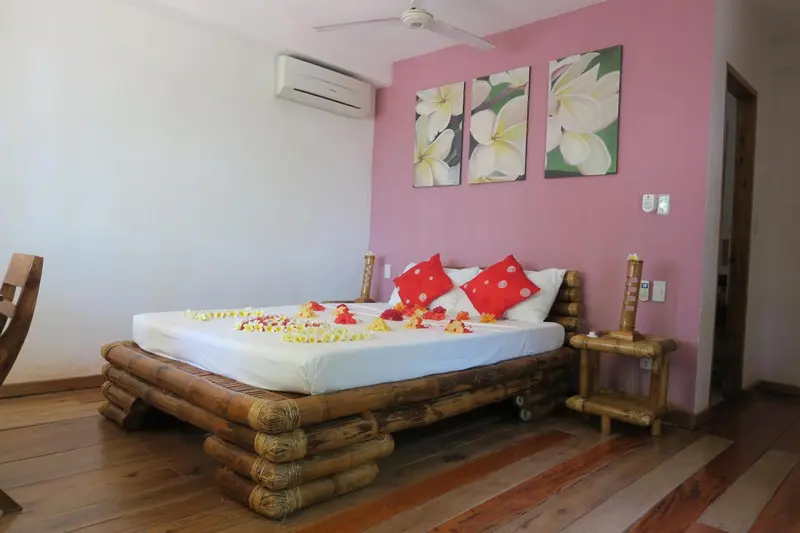 Une chambre décorée avec un lit en bambou et des fleurs.