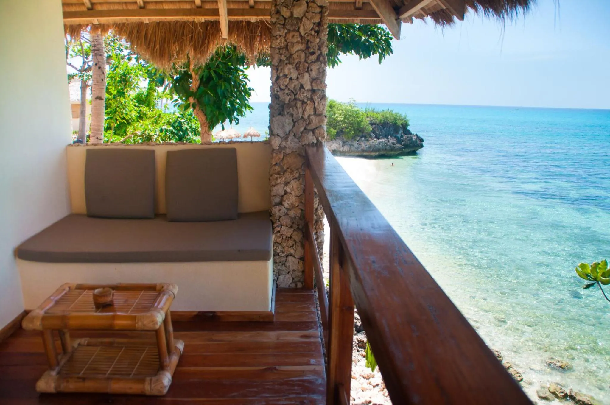 Vue sur la mer depuis une terrasse aménagée avec un canapé et une table basse.