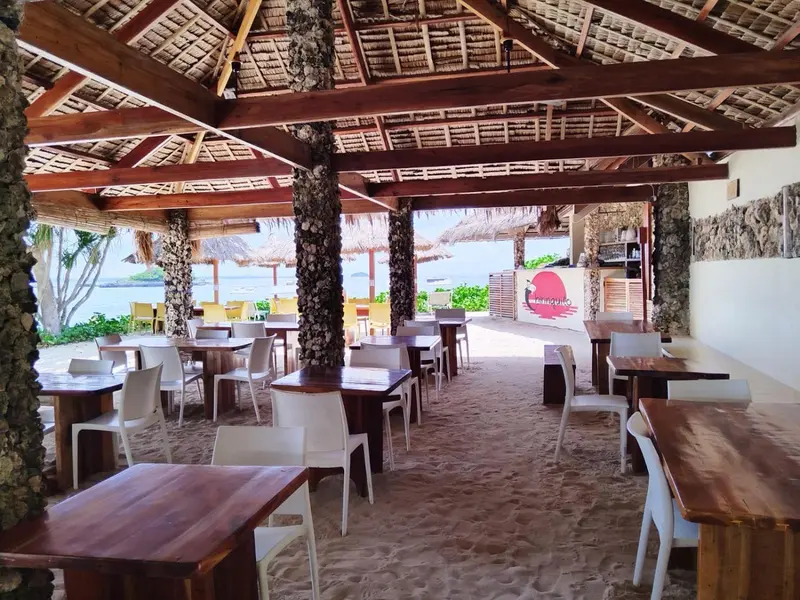 Une salle à manger en plein air avec des tables en bois et des chaises blanches.