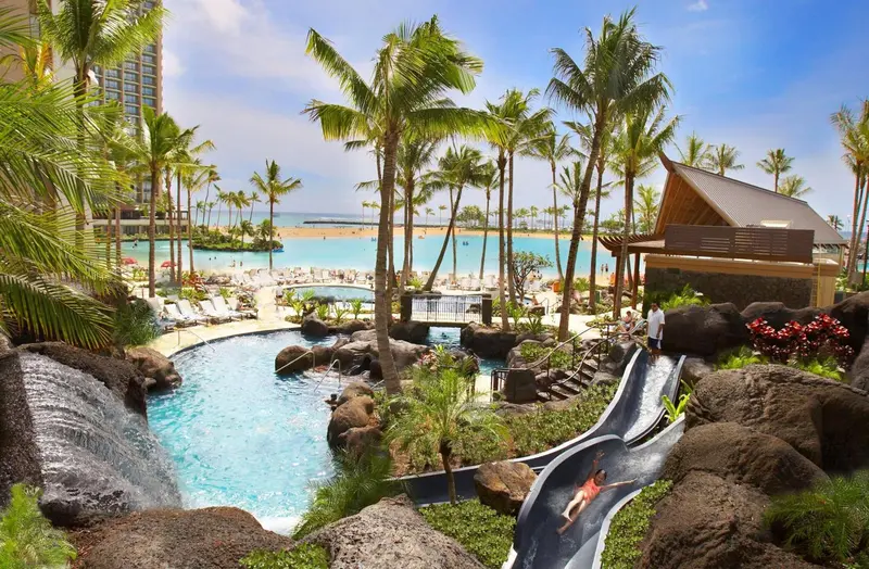 Vue aérienne d'une piscine avec toboggan au sein d'un complexe hôtelier tropical.