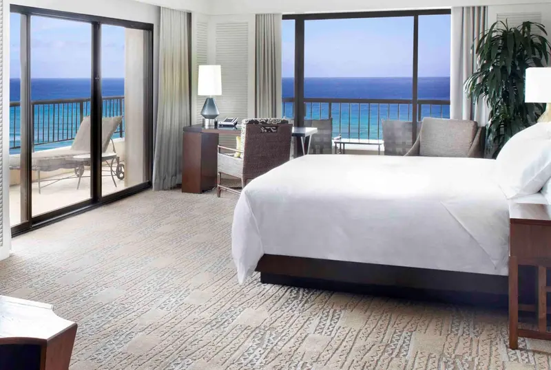 Une chambre lumineuse avec un grand lit et un accès à un balcon avec vue sur la mer.