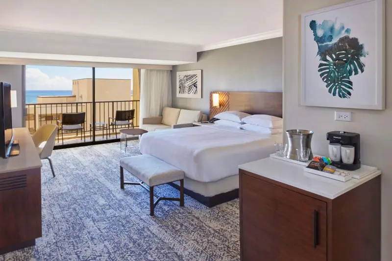 Une chambre d'hôtel lumineuse avec un grand lit et un accès à un balcon.
