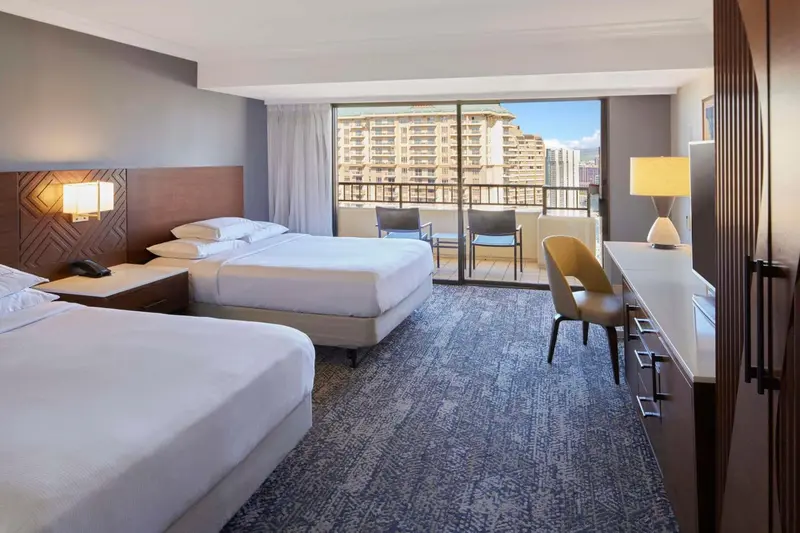 Chambre d'hôtel avec deux lits et balcon offrant une vue sur la ville.