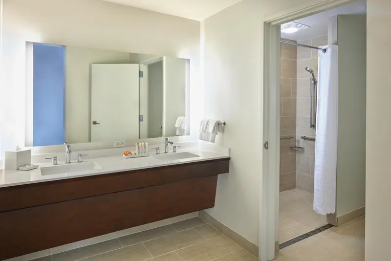 Une salle de bain lumineuse avec deux vasques et une douche.