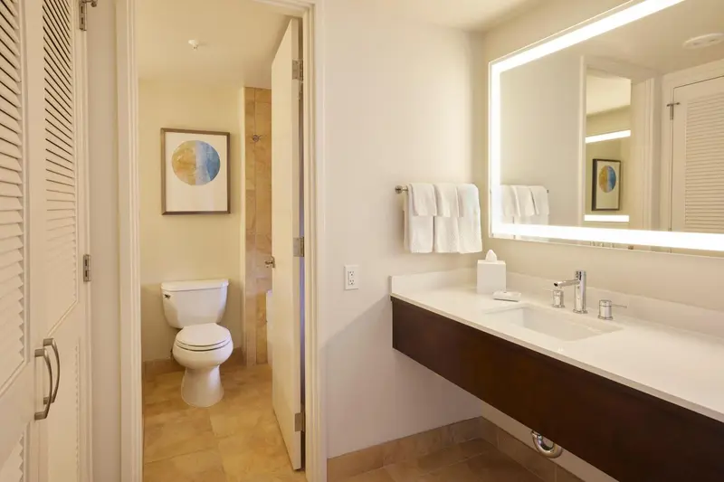 Une salle de bain lumineuse avec lavabo, miroir et toilettes.