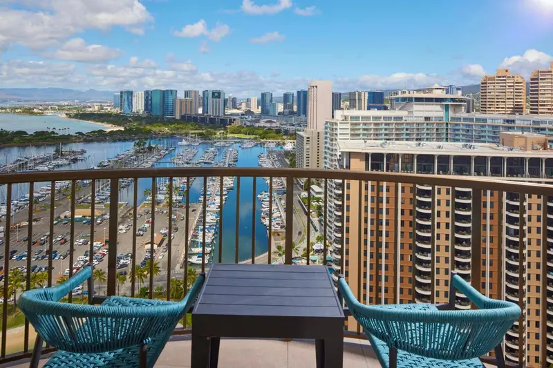 Vue d'une terrasse avec mobilier et panorama sur la ville et la mer.