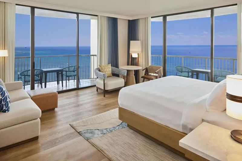 Une chambre lumineuse avec un grand lit et un coin salon donnant sur la mer.