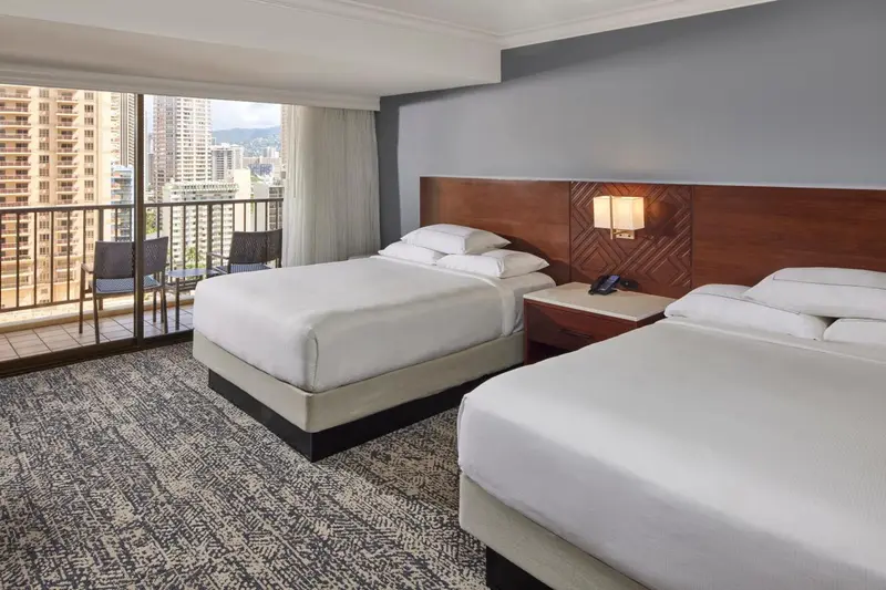 Une chambre d'hôtel avec un grand lit et un balcon offrant une vue sur la ville.
