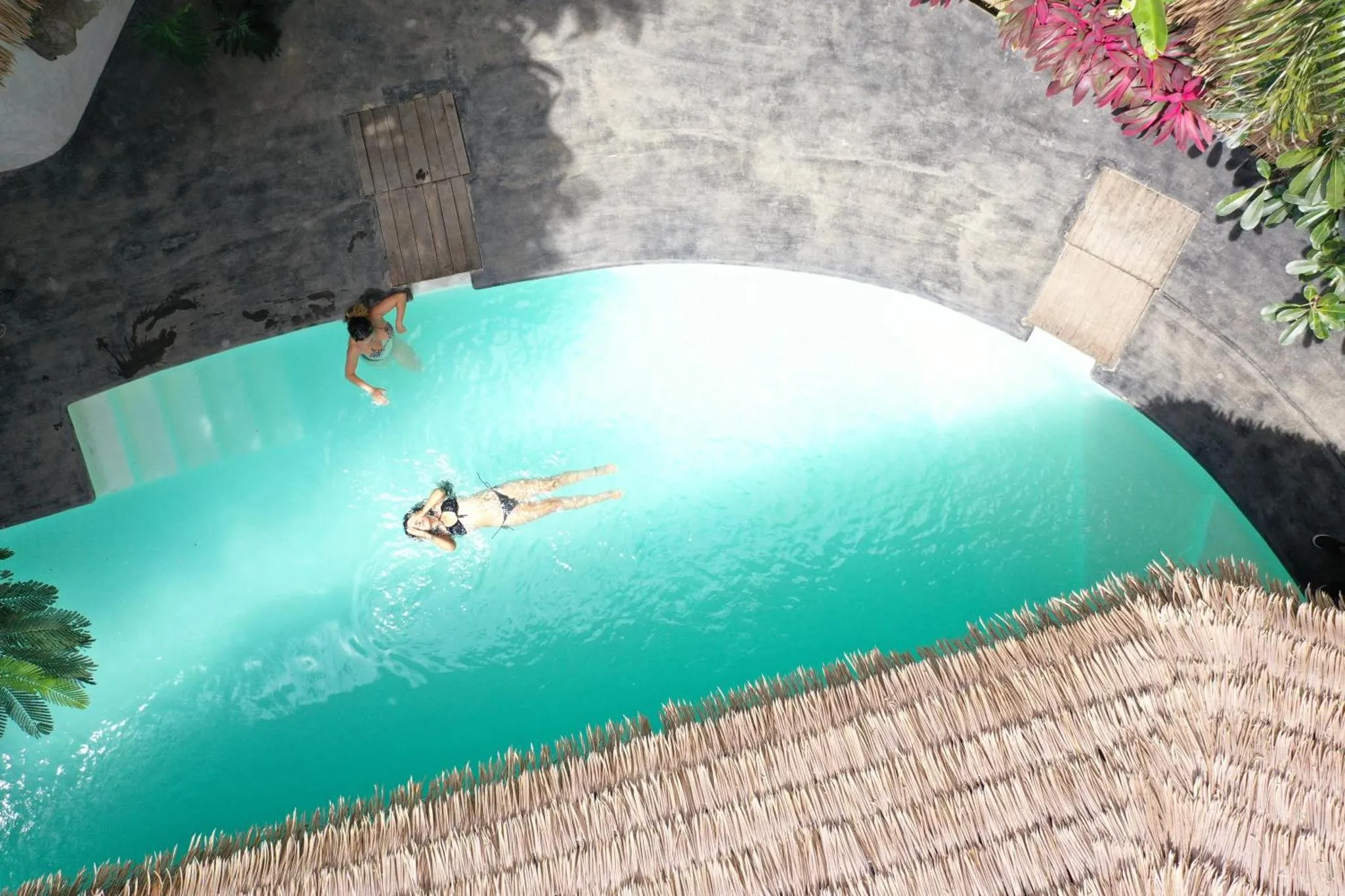 Deux personnes se détendent dans une piscine turquoise.