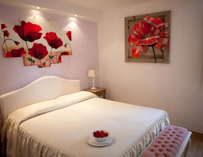 Une chambre lumineuse avec un grand lit recouvert d'une courtepointe blanche et une décoration florale.