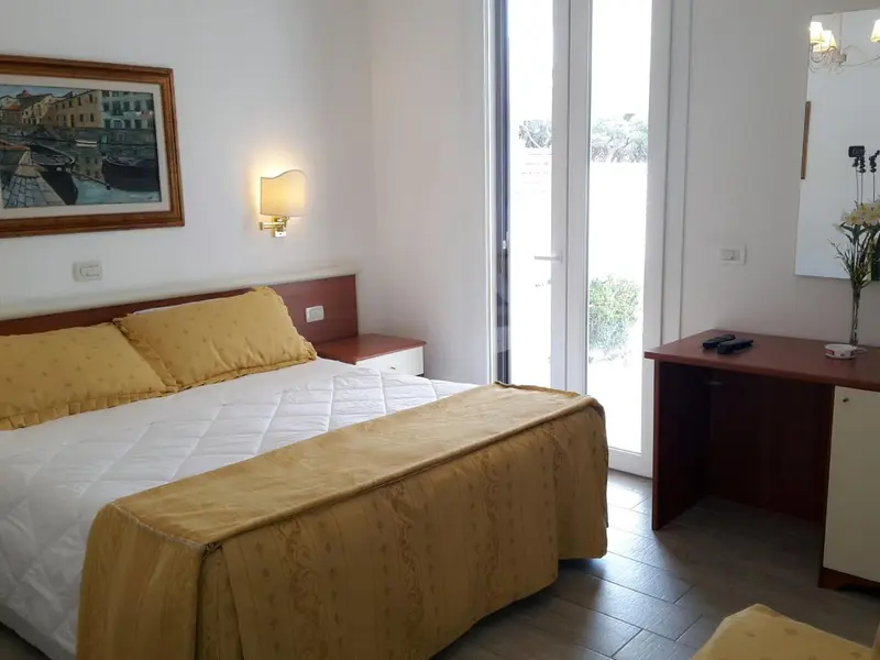 Une chambre lumineuse avec un grand lit recouvert d'une courtepointe jaune et un bureau en bois.