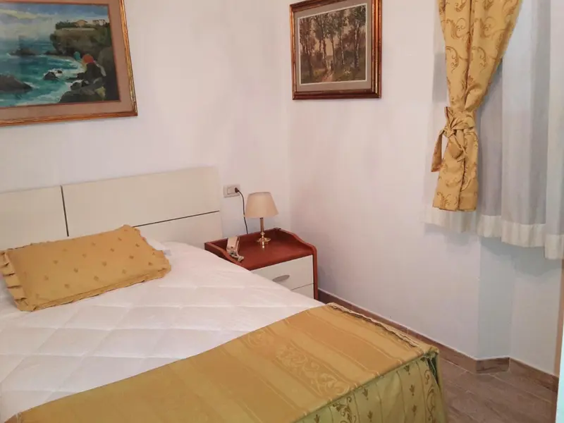 Une chambre lumineuse avec un lit recouvert d'une courtepointe jaune et des tableaux décoratifs.