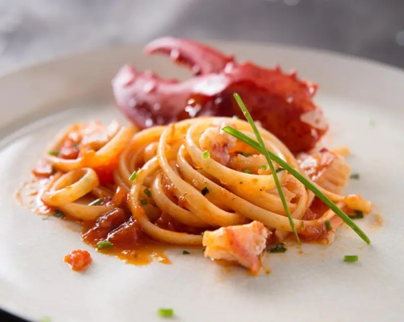Assiette de spaghetti aux fruits de mer avec une portion de homard.