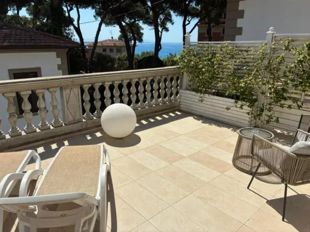 Terrasse ensoleillée avec mobilier d'extérieur et vue sur la mer.