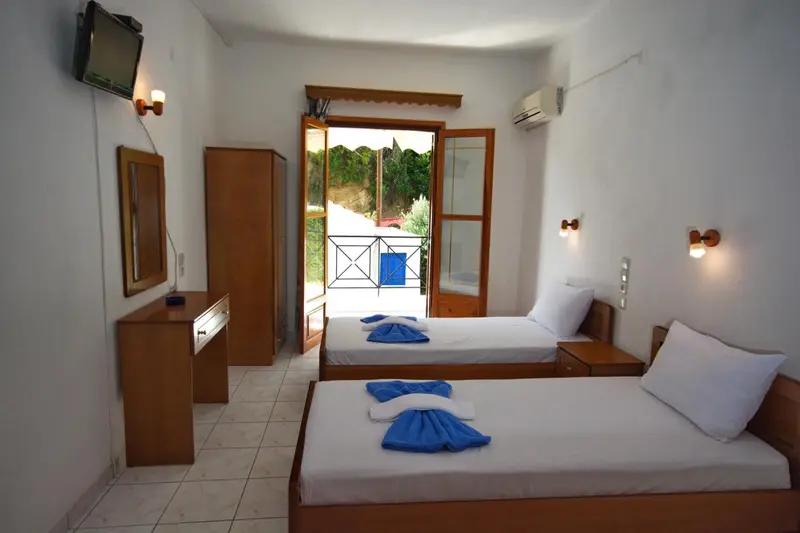 Une chambre lumineuse avec deux lits simples et un accès à une terrasse.