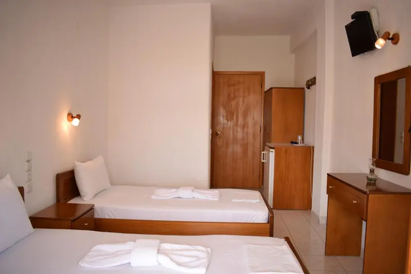 Une chambre lumineuse avec deux lits simples et un meuble de rangement.