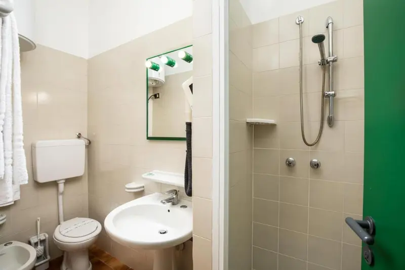 Une salle de bain claire avec douche, lavabo et toilettes.