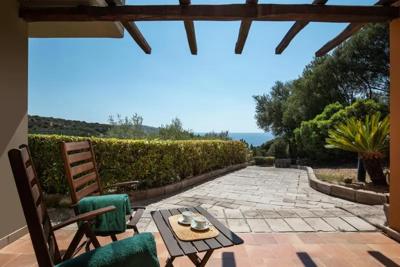 Une terrasse pavée offre une vue dégagée sur la végétation et la mer.