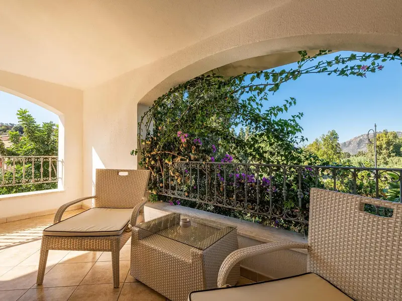 Terrasse aménagée avec mobilier en rotin et vue sur la végétation.