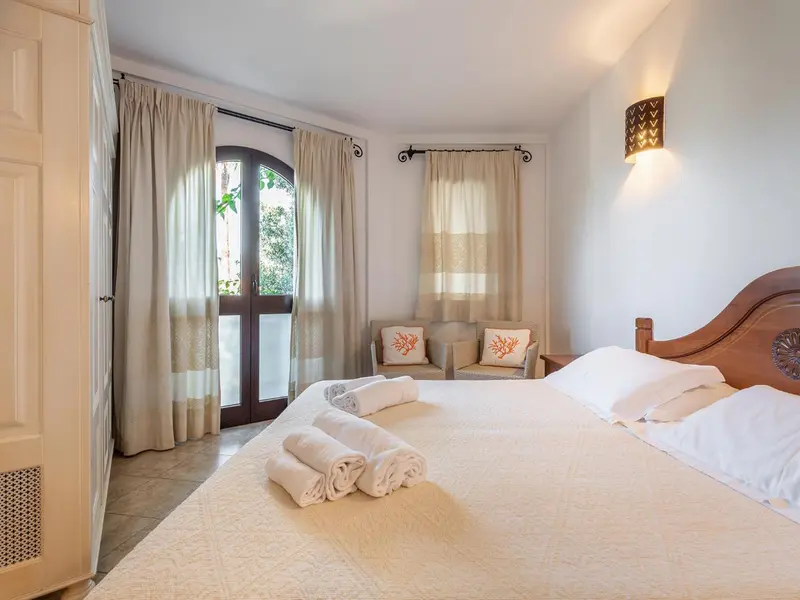 Une chambre lumineuse avec un grand lit et un accès à une terrasse.