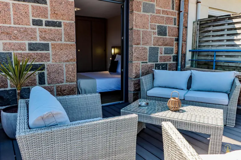 Terrasse aménagée avec salon et vue sur une chambre.
