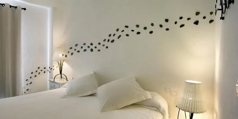 Un lit blanc avec des oreillers dans une chambre décorée d'un motif de poissons sur le mur.