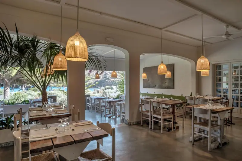 Une salle à manger lumineuse avec des tables en bois et des luminaires en osier.