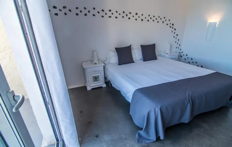 Une chambre lumineuse avec un lit double et des oreillers gris.