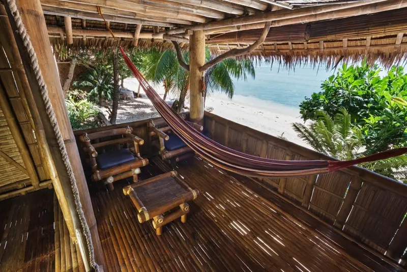 Espace de détente en bois avec hamac et mobilier de jardin face à la mer.