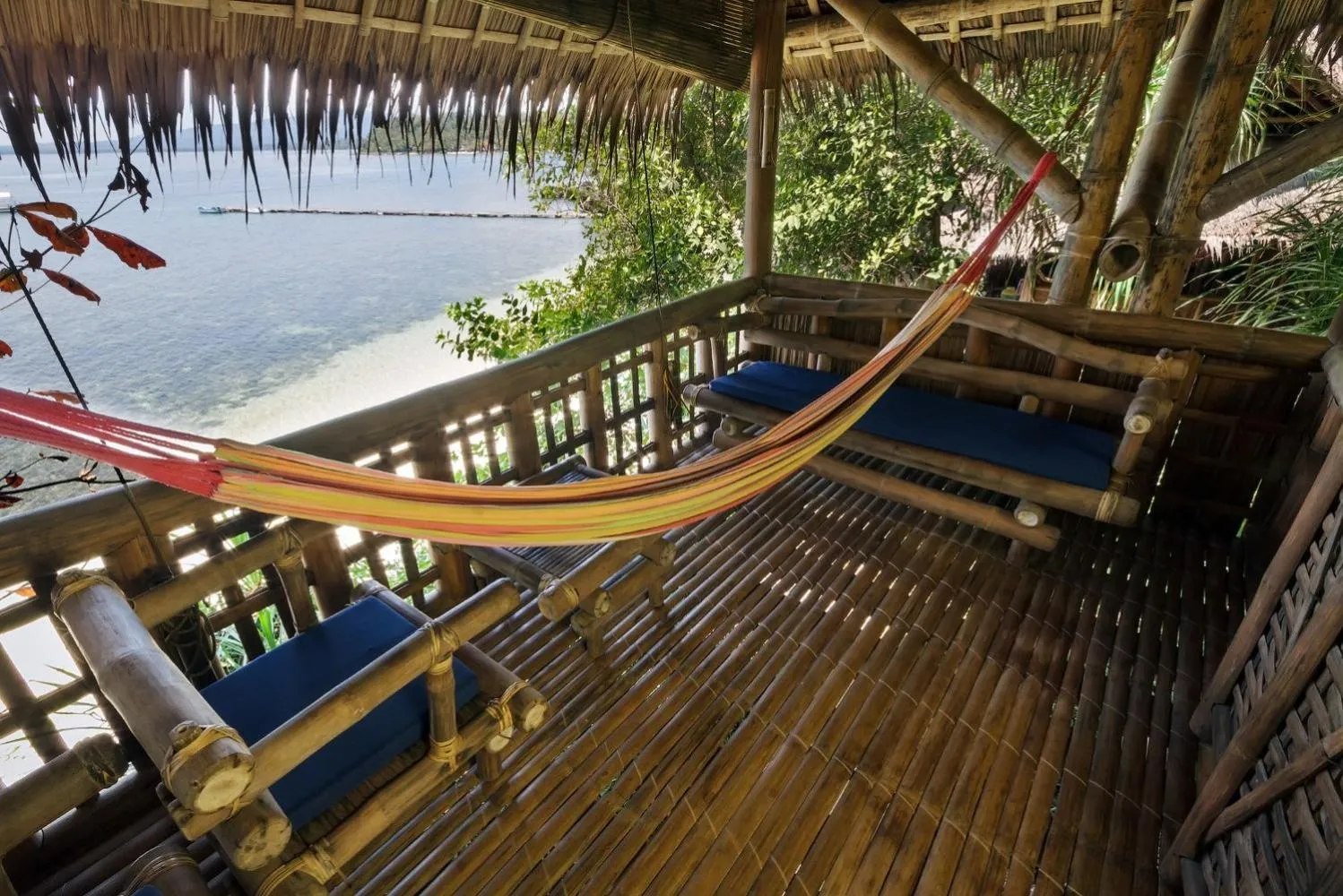 Terrasse en bois avec hamac et vue sur la mer.