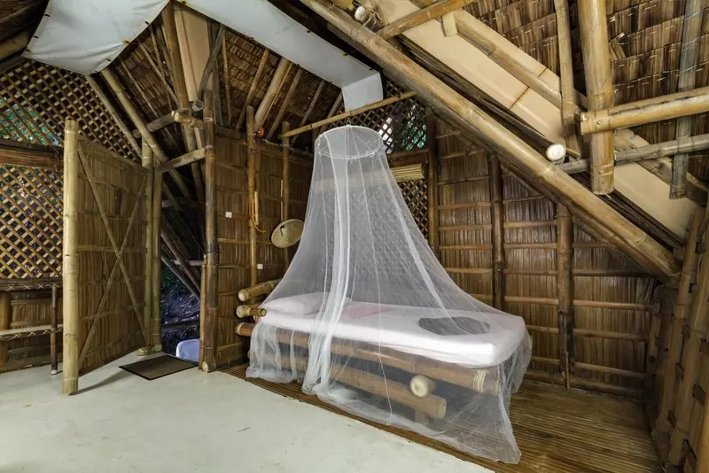 Une chambre rustique avec un lit à baldaquin en bambou.