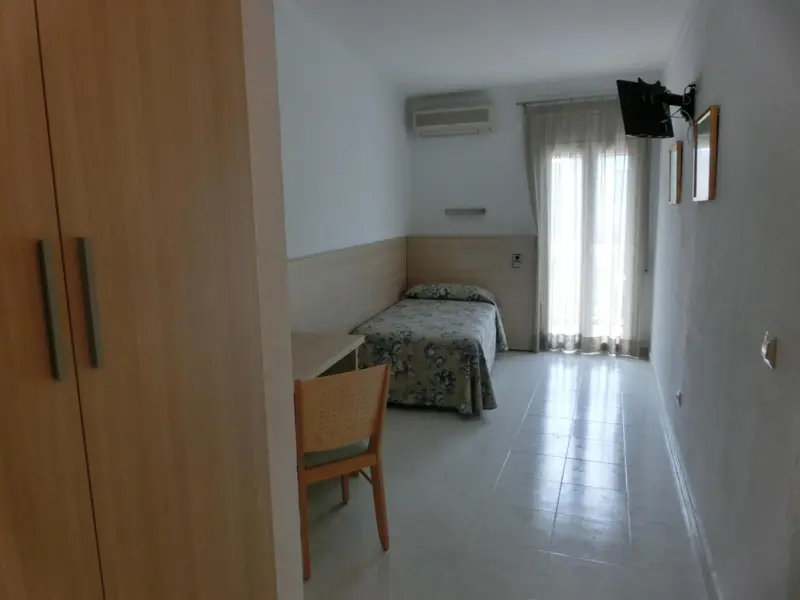 Une chambre lumineuse avec un lit simple et un bureau.