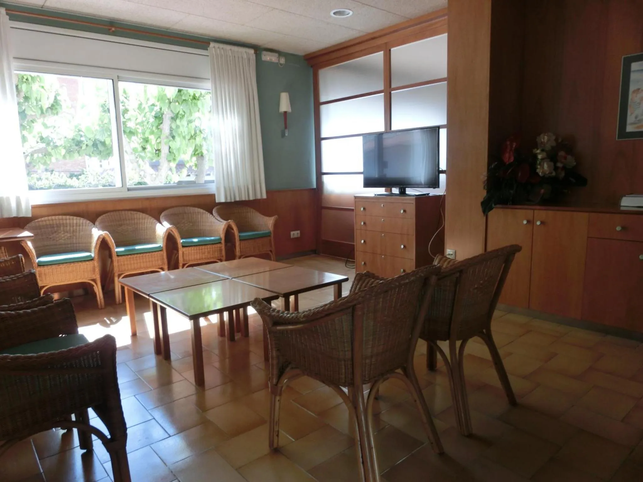 Espace de détente lumineux avec mobilier en rotin et télévision.
