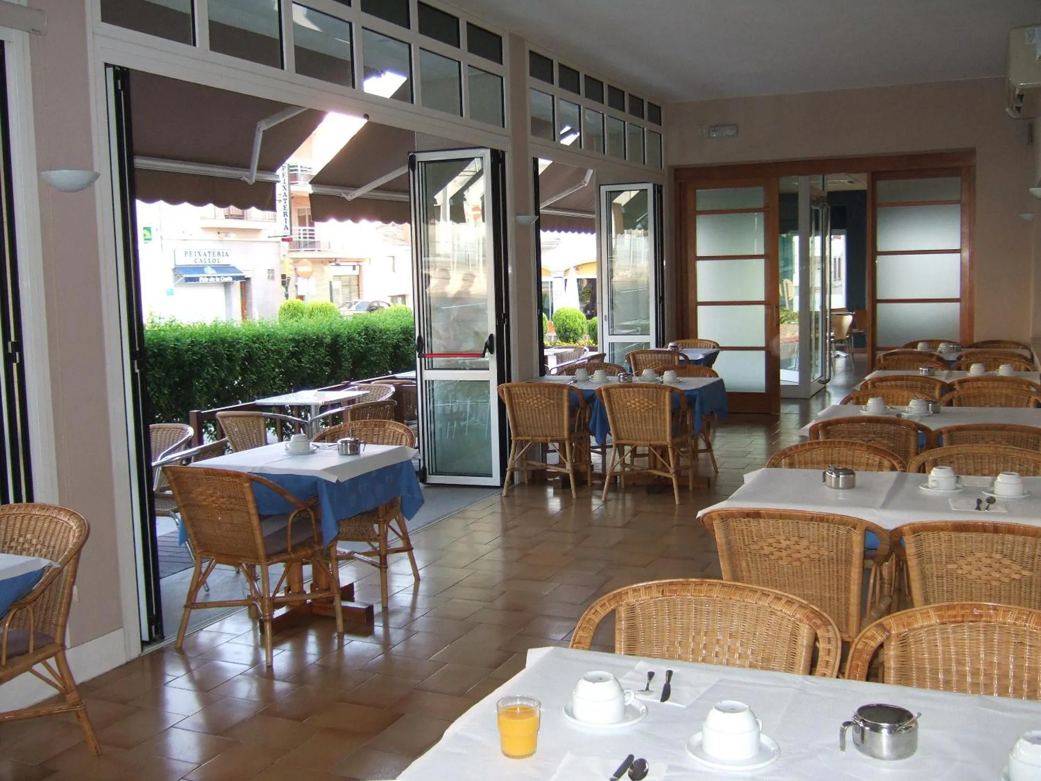 Une salle lumineuse avec des tables dressées pour le petit-déjeuner.