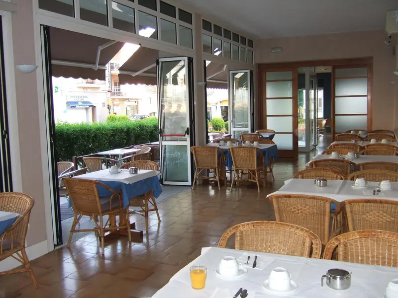 Une salle lumineuse avec des tables dressées pour le petit-déjeuner.