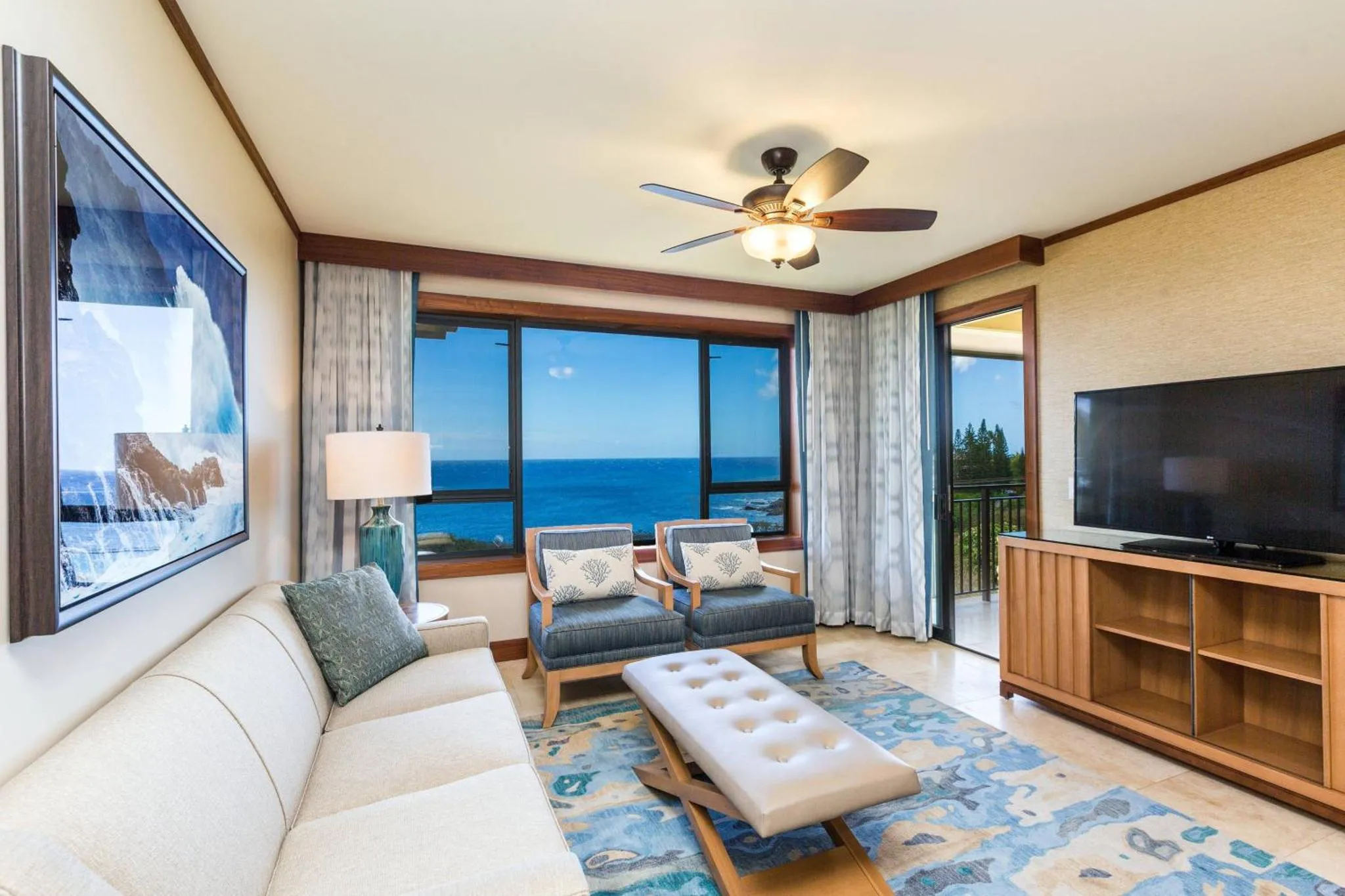 Espace de détente lumineux avec canapé, fauteuils et vue sur la mer.