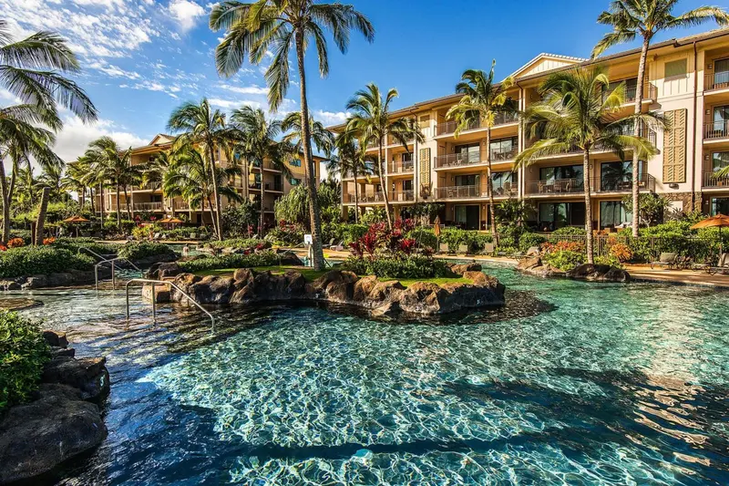 Vue d'un complexe hôtelier tropical avec une piscine sinueuse et une végétation luxuriante.