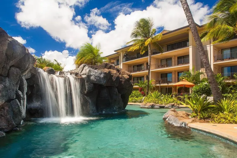Une cascade se jette dans un bassin turquoise au milieu d'une végétation luxuriante.