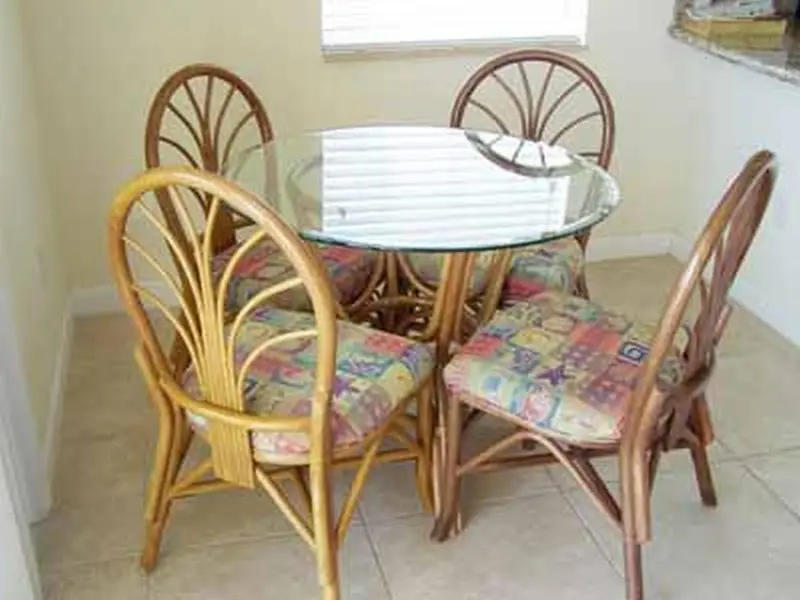 Table ronde en osier et chaises assorties dans une pièce lumineuse.