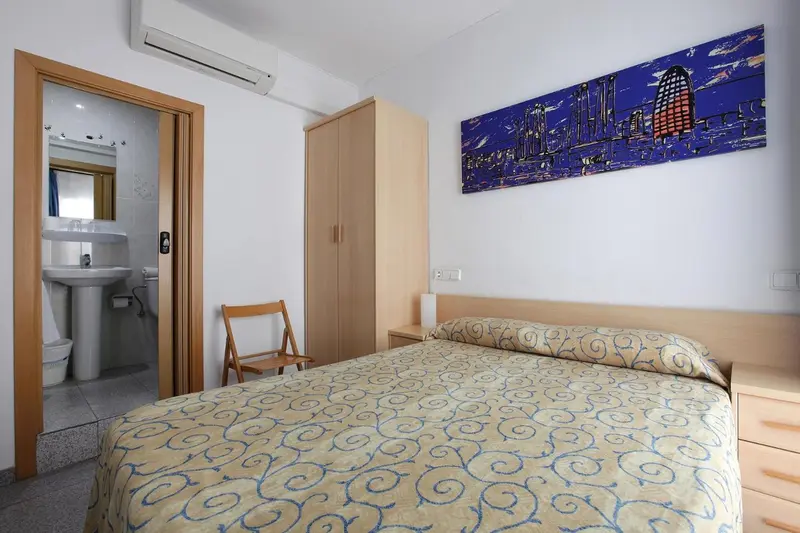 Une chambre lumineuse avec un lit recouvert d'une courtepointe à motifs et un accès à une salle de bain.